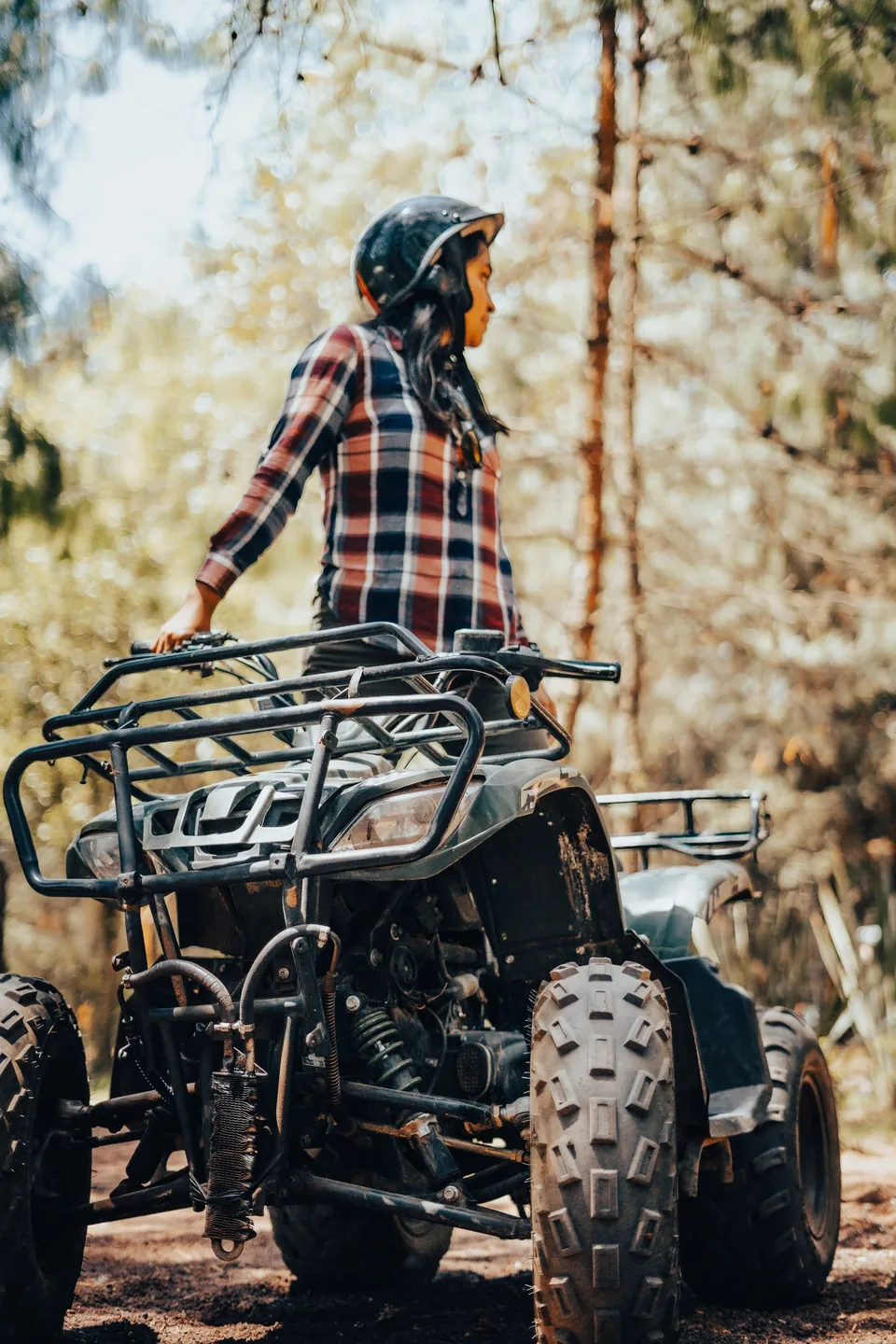 Personne casquée près d’un quad sur un chemin forestier