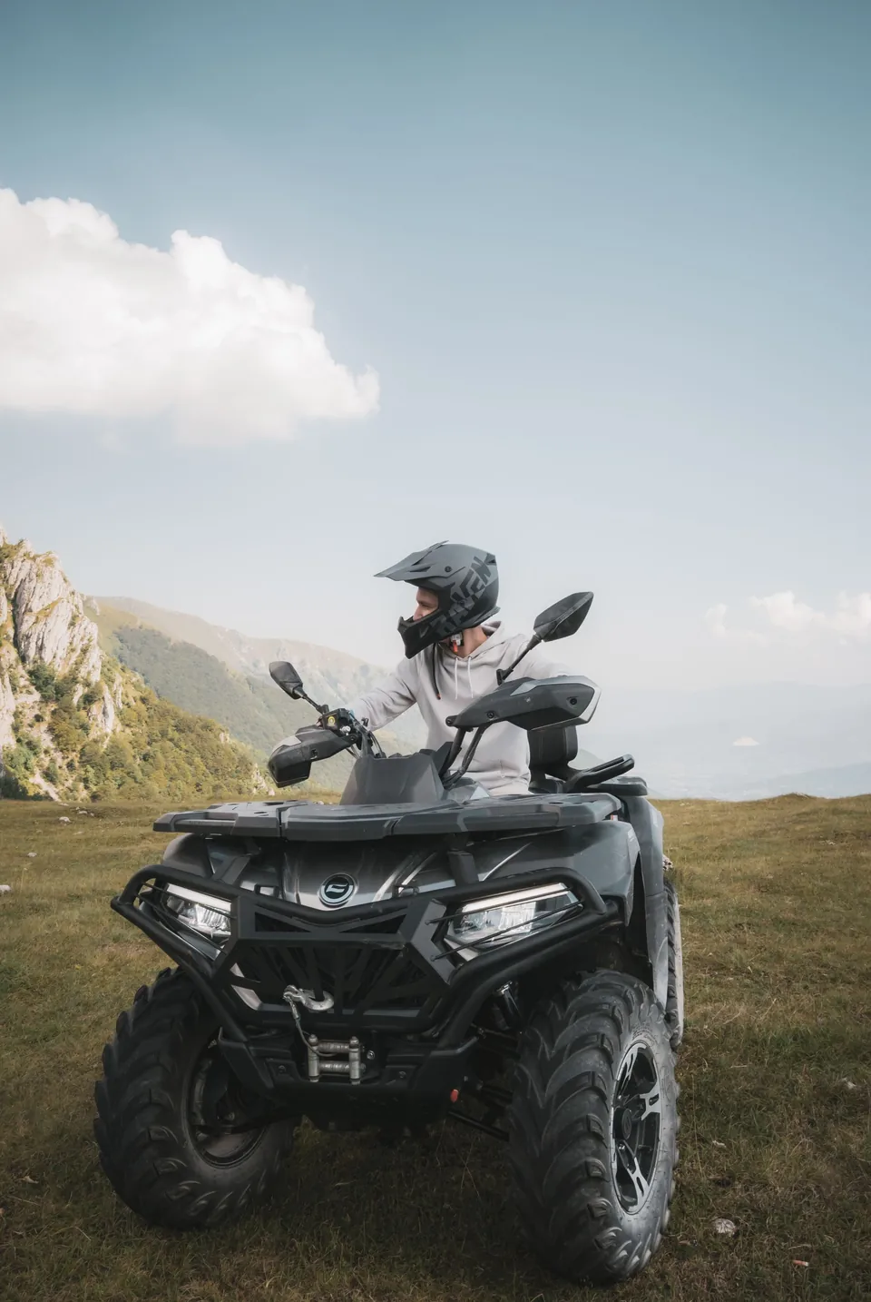 Pilote casqué sur un quad dans un paysage vallonné